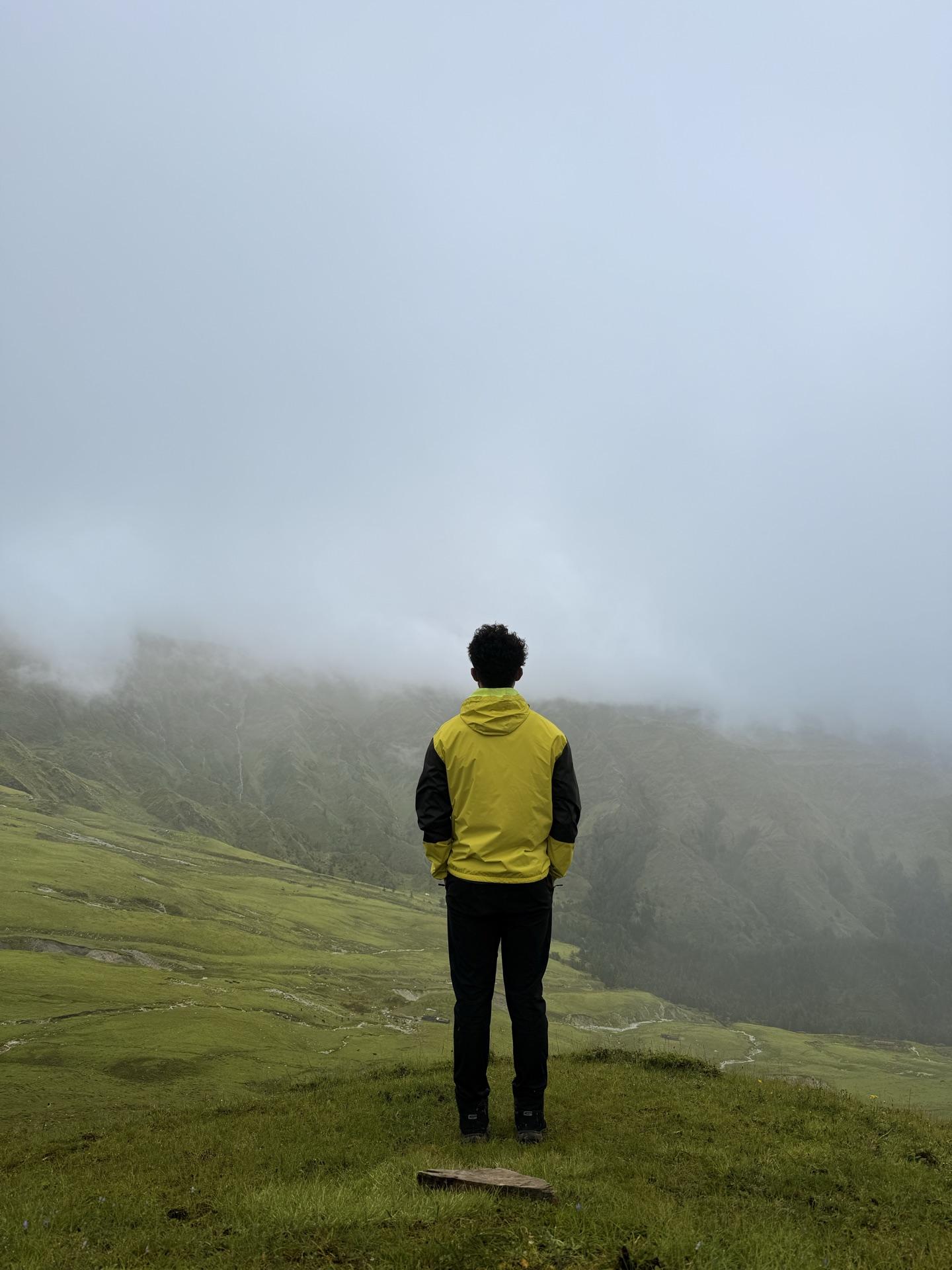 A friend in a yellow jacket standing before a solid wall of white cloud