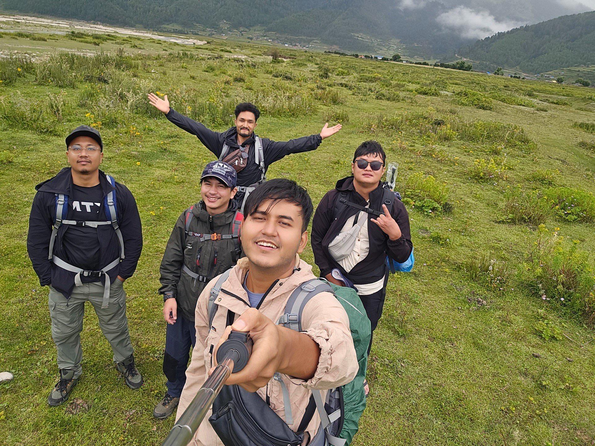 Five friends posing on an open green pasture under cloud-wrapped hills