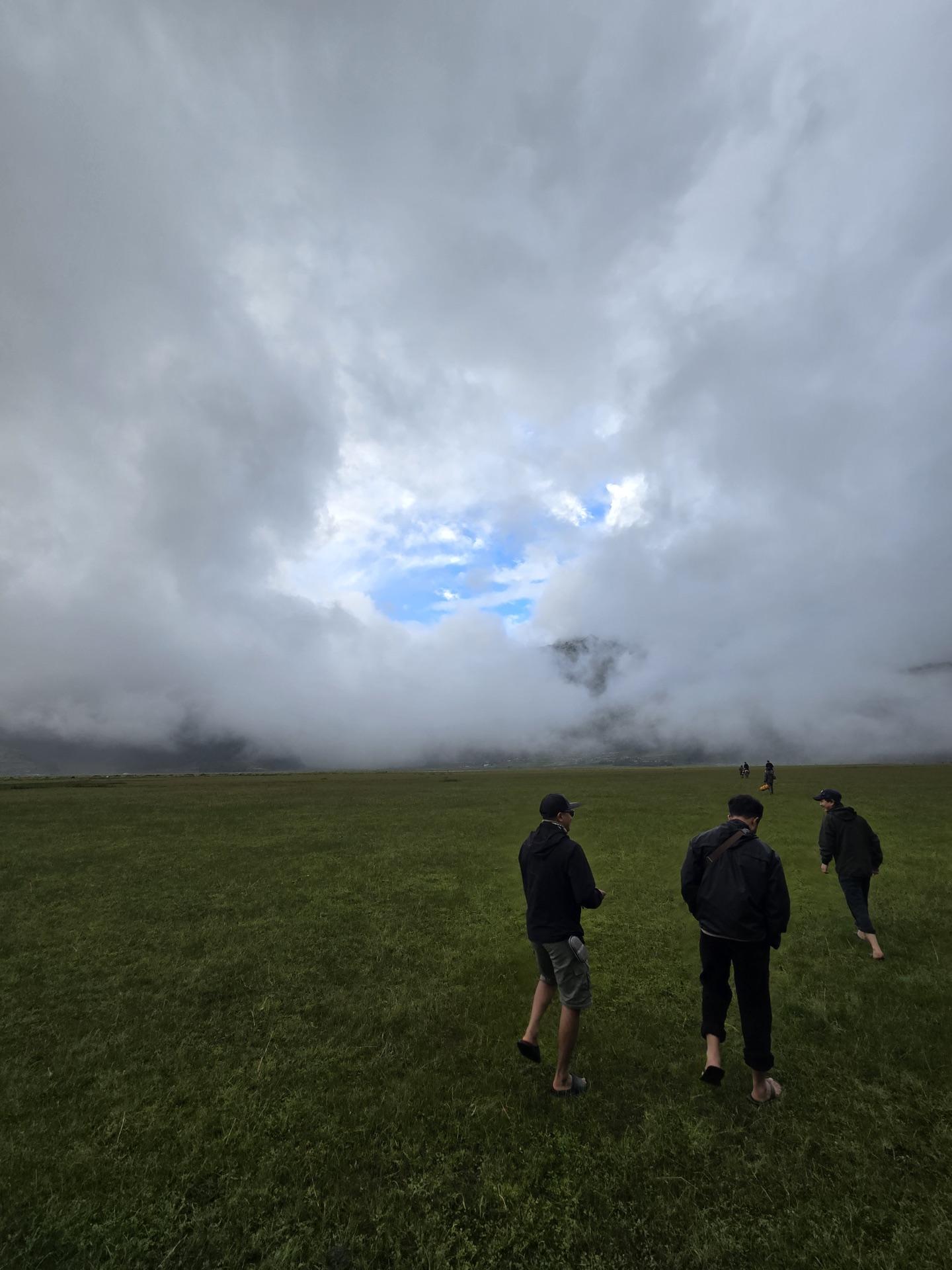 Three friends walking the darkening pasture under a huge broken sky