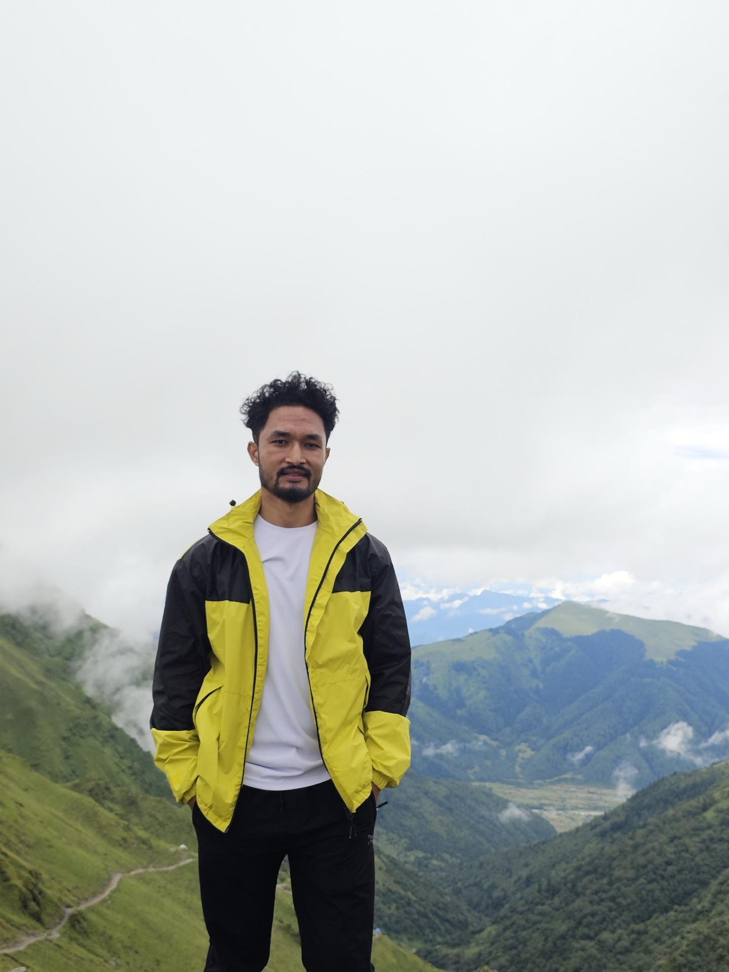 A friend in a yellow jacket standing above the deep green valley