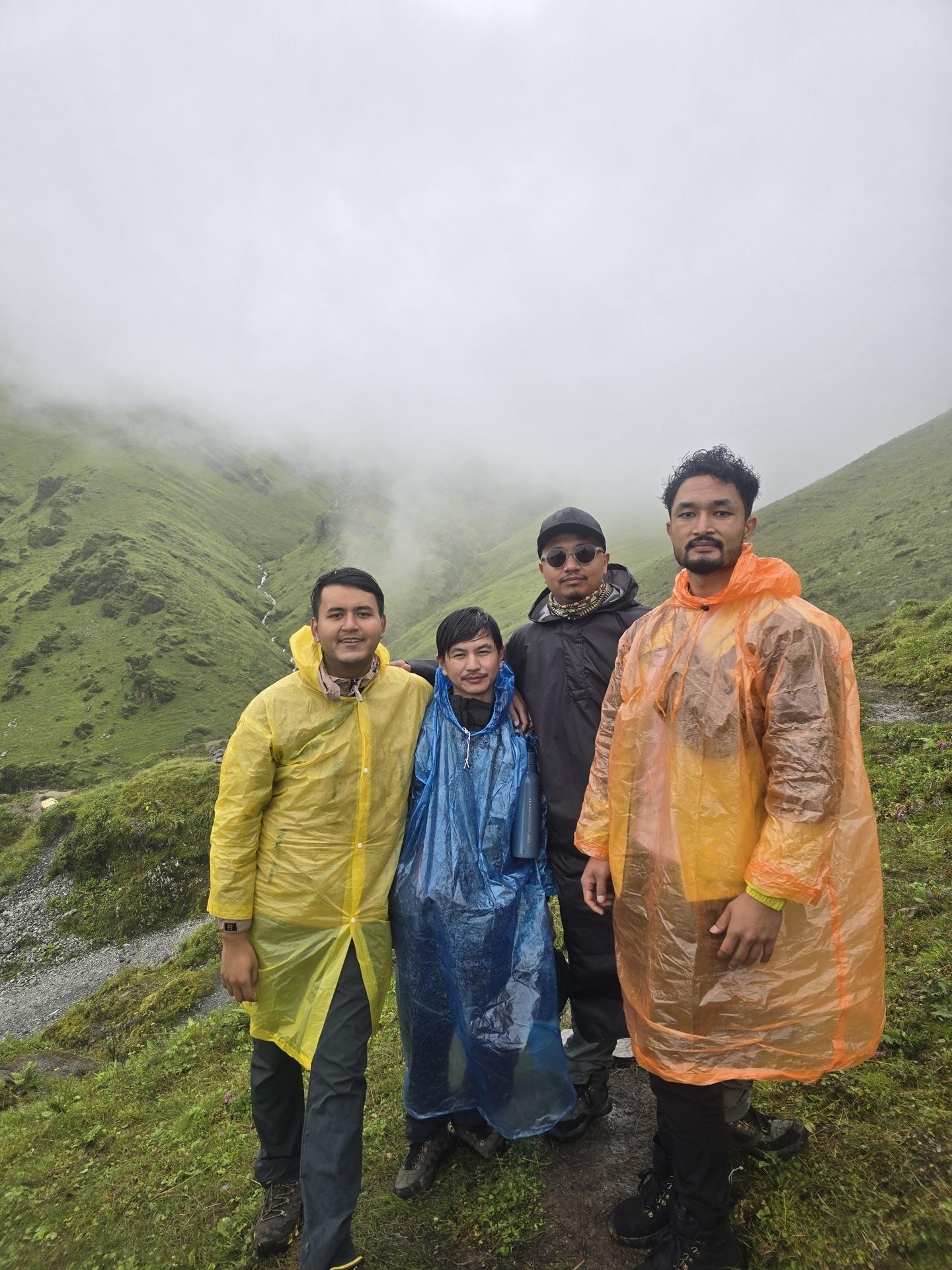 Four friends in colorful rain ponchos posing on the misty trail