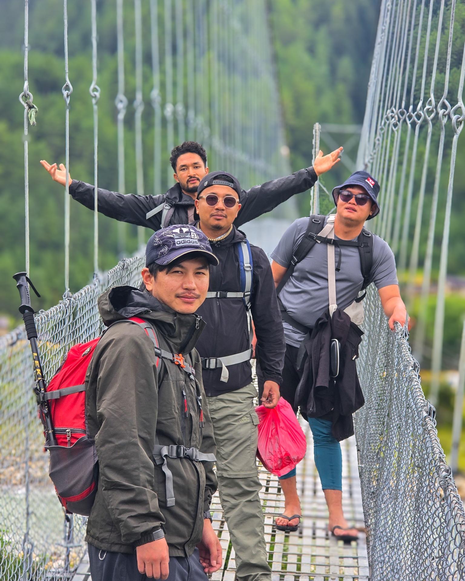All five friends posing on the suspension bridge with full packs on the way out