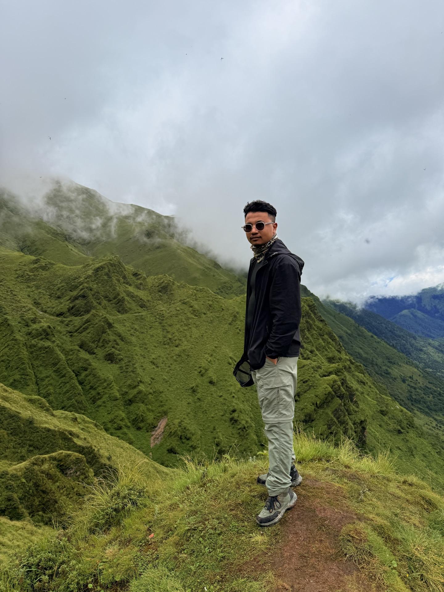A friend standing at the green ridge edge, cloud pouring over the far wall