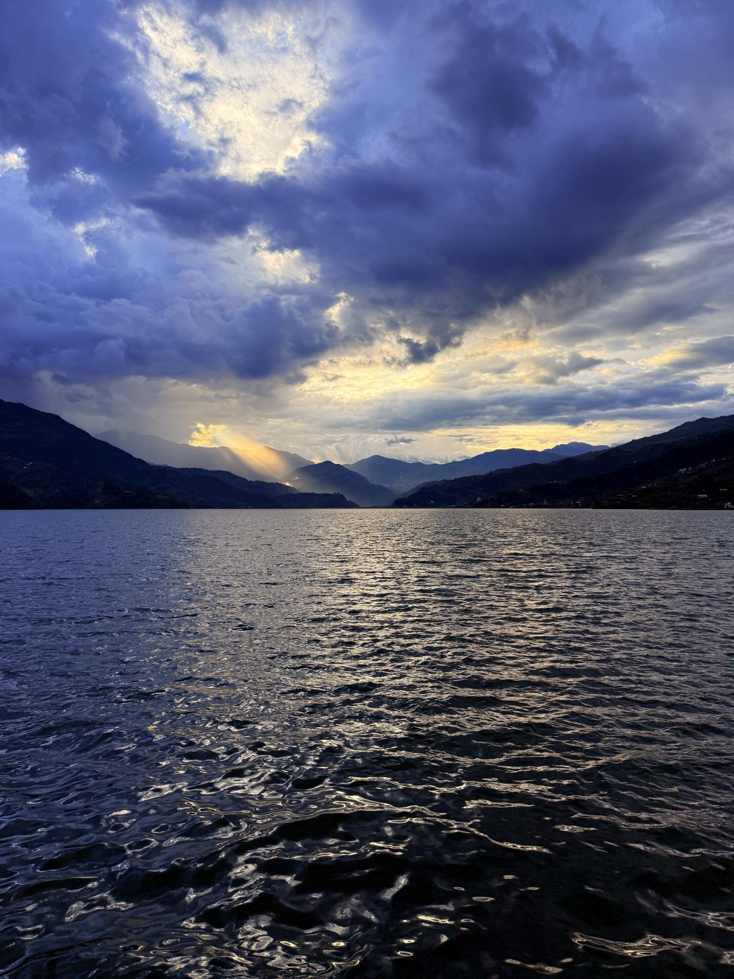 Sunbeams breaking through heavy clouds over Phewa Lake