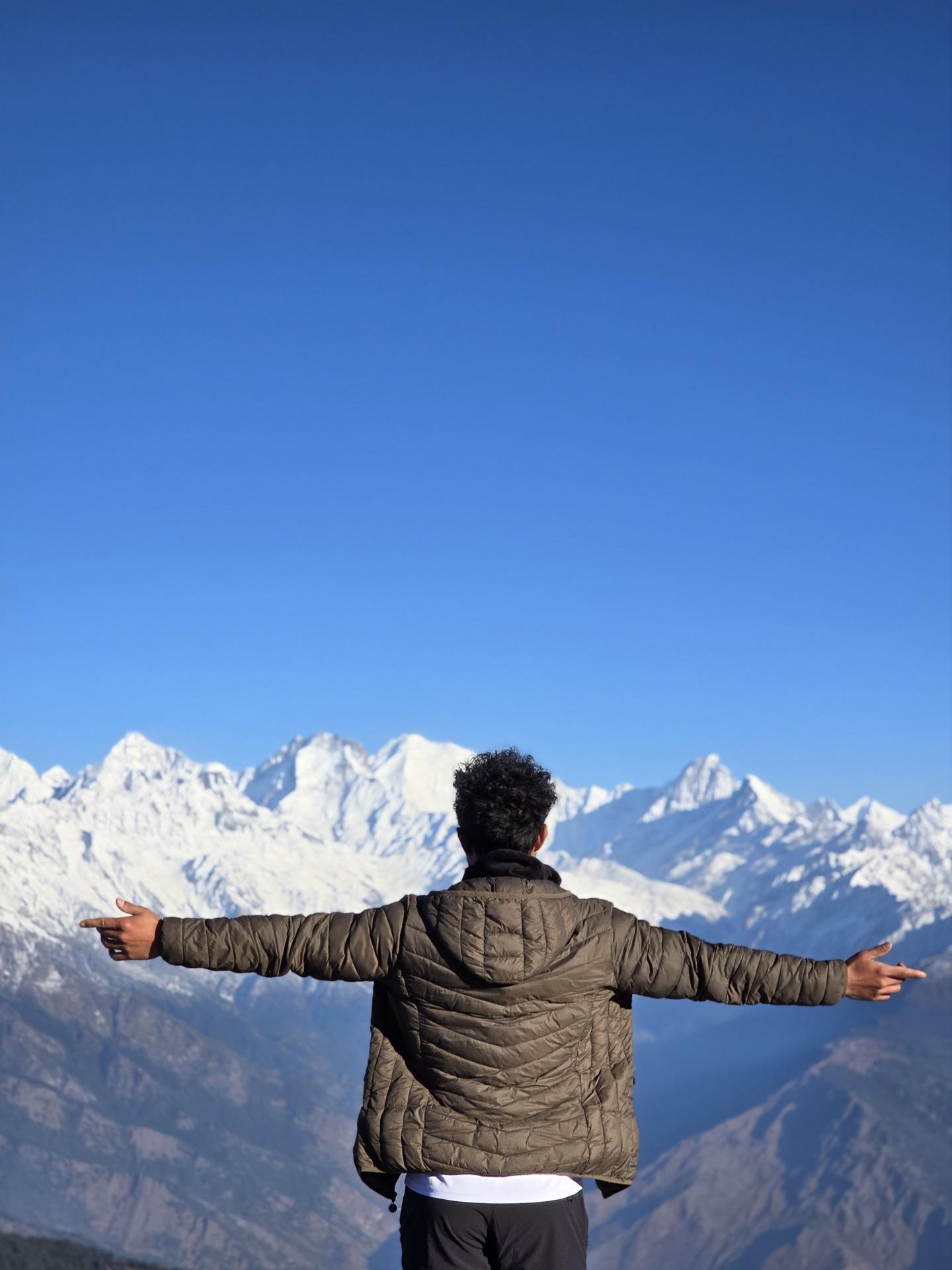 A friend with arms spread wide facing the gold morning range