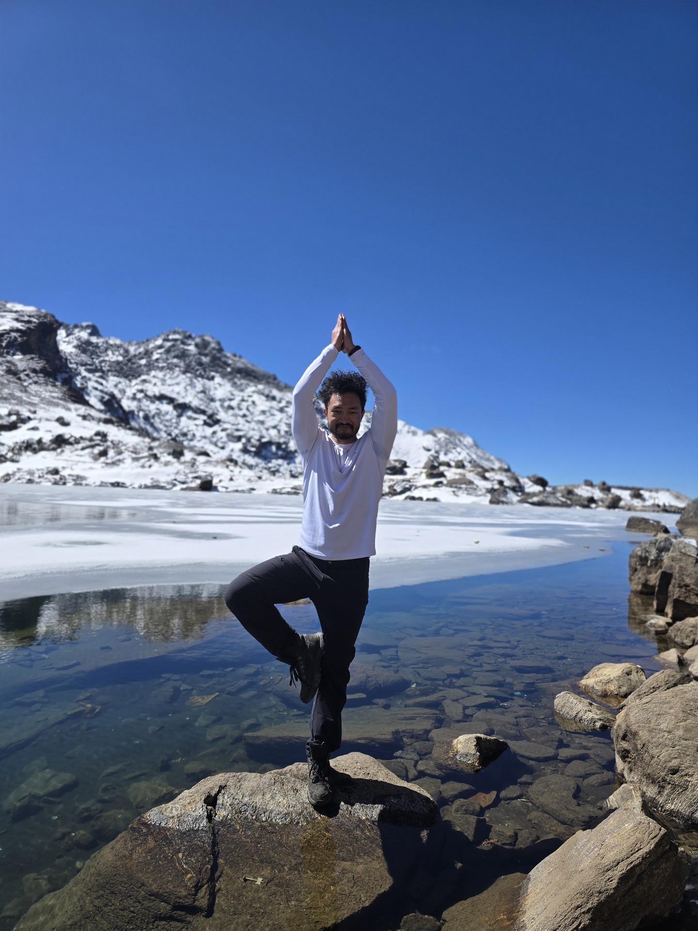 A friend balancing in tree pose on a shoreline rock