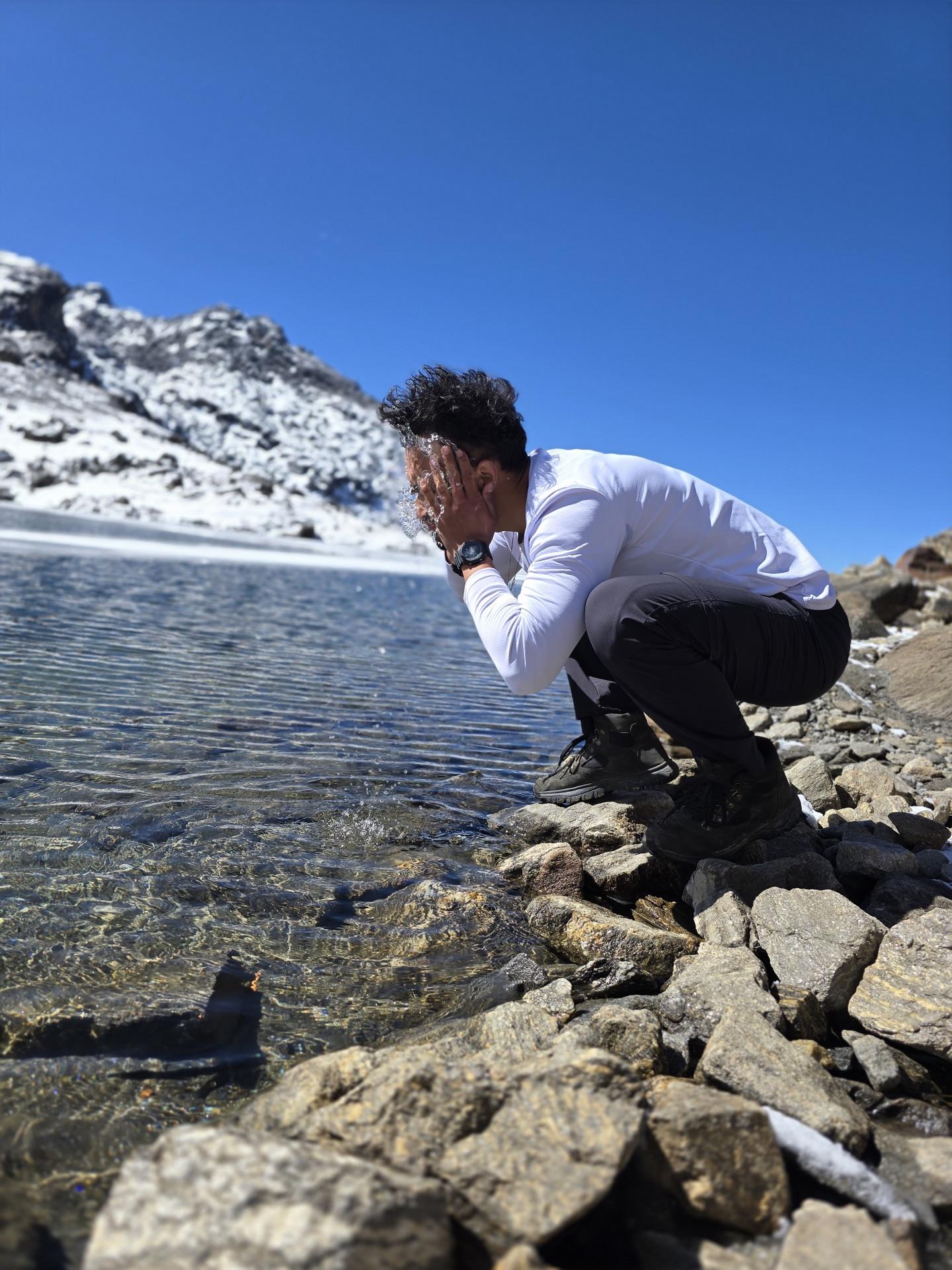A friend crouched at the shoreline touching the water