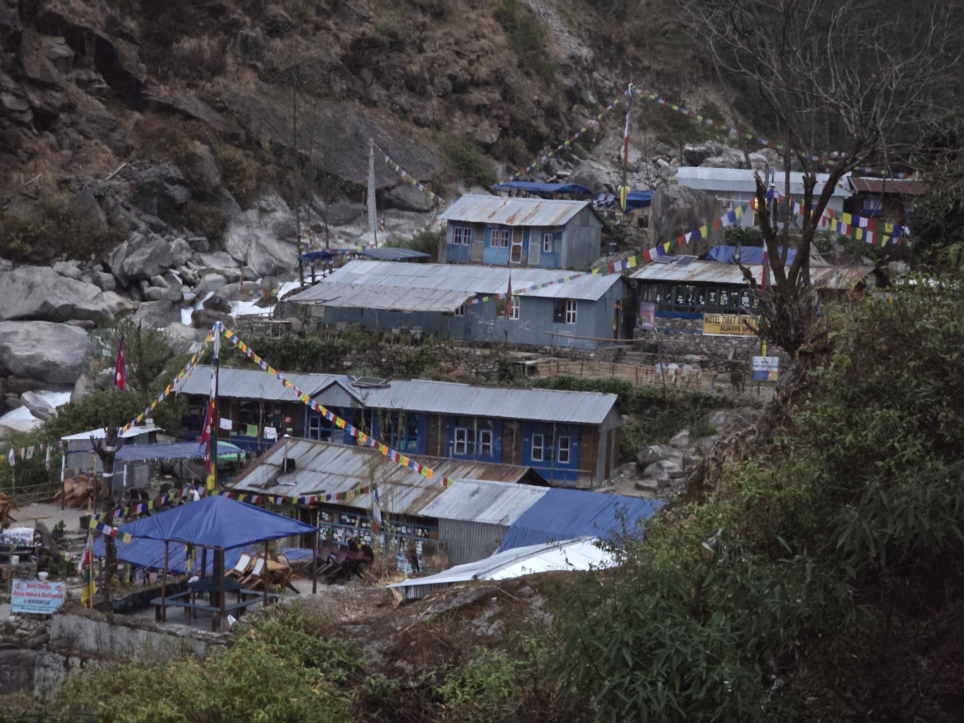 Tin-roofed teahouses with prayer flags in the gorge at dusk