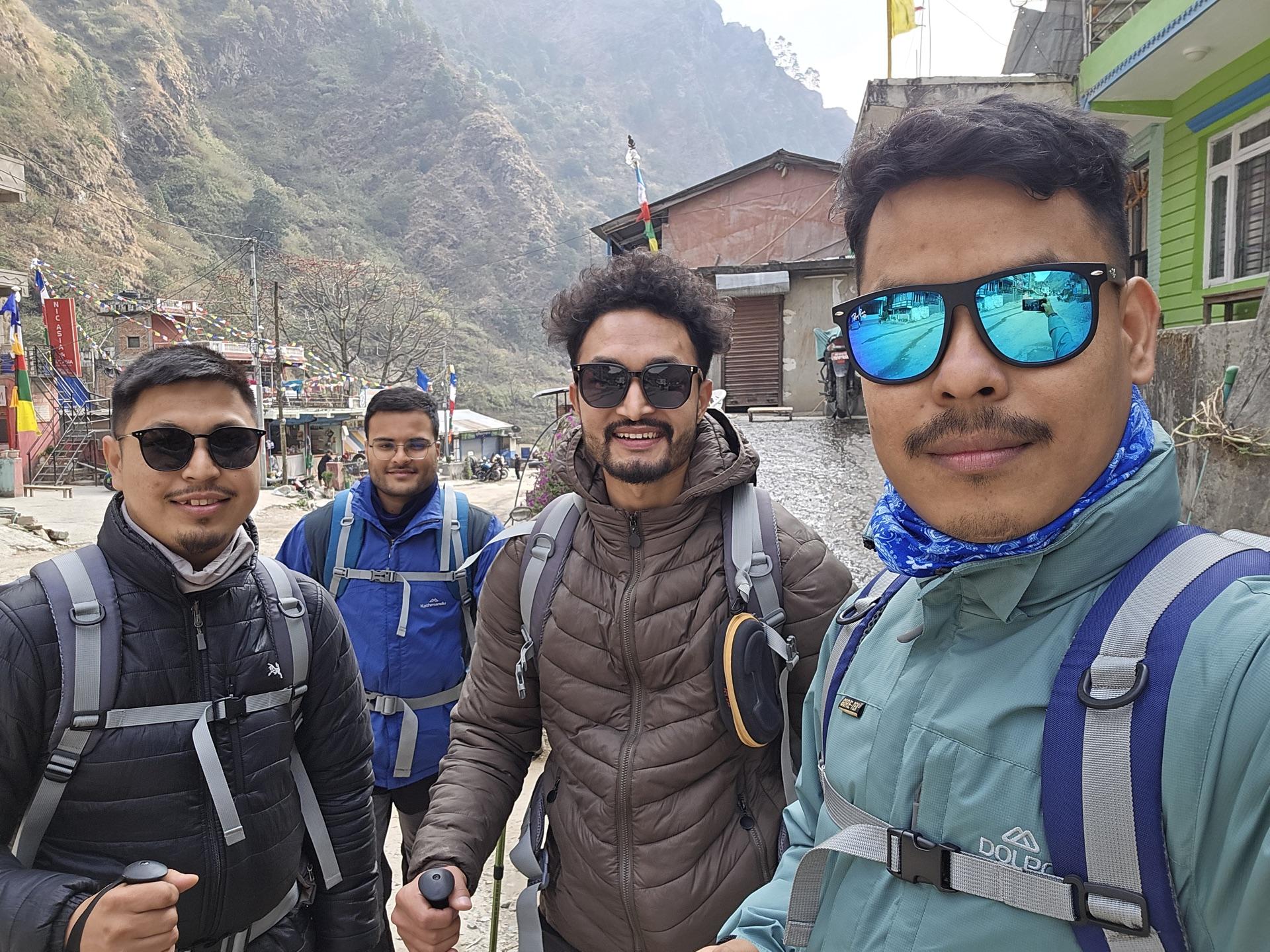 Four friends with backpacks taking a selfie in the streets of Syabrubesi