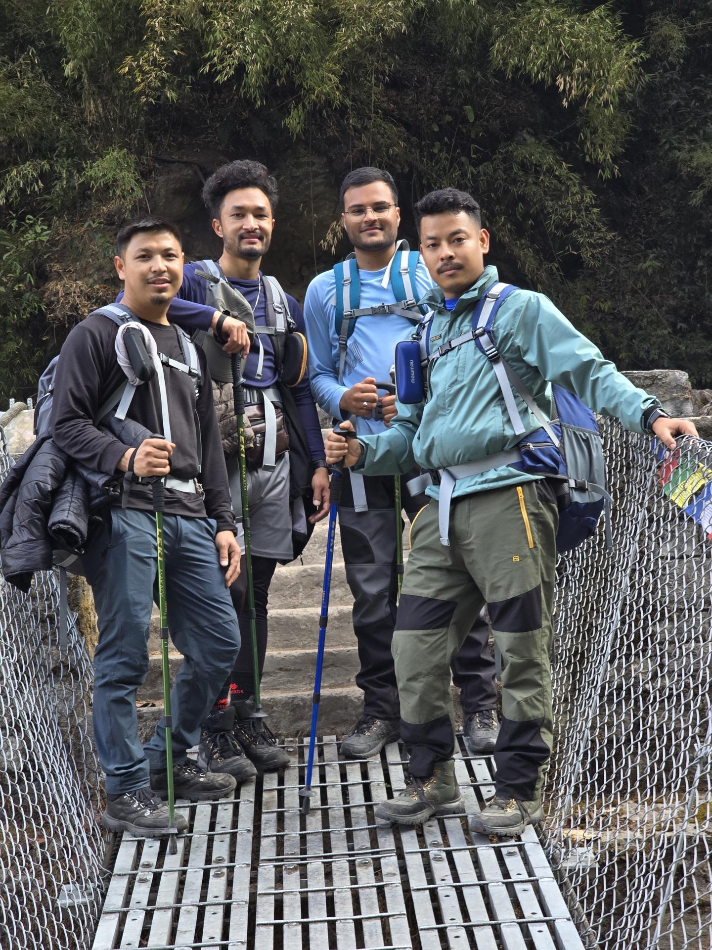 All four friends posing together mid-bridge with their poles