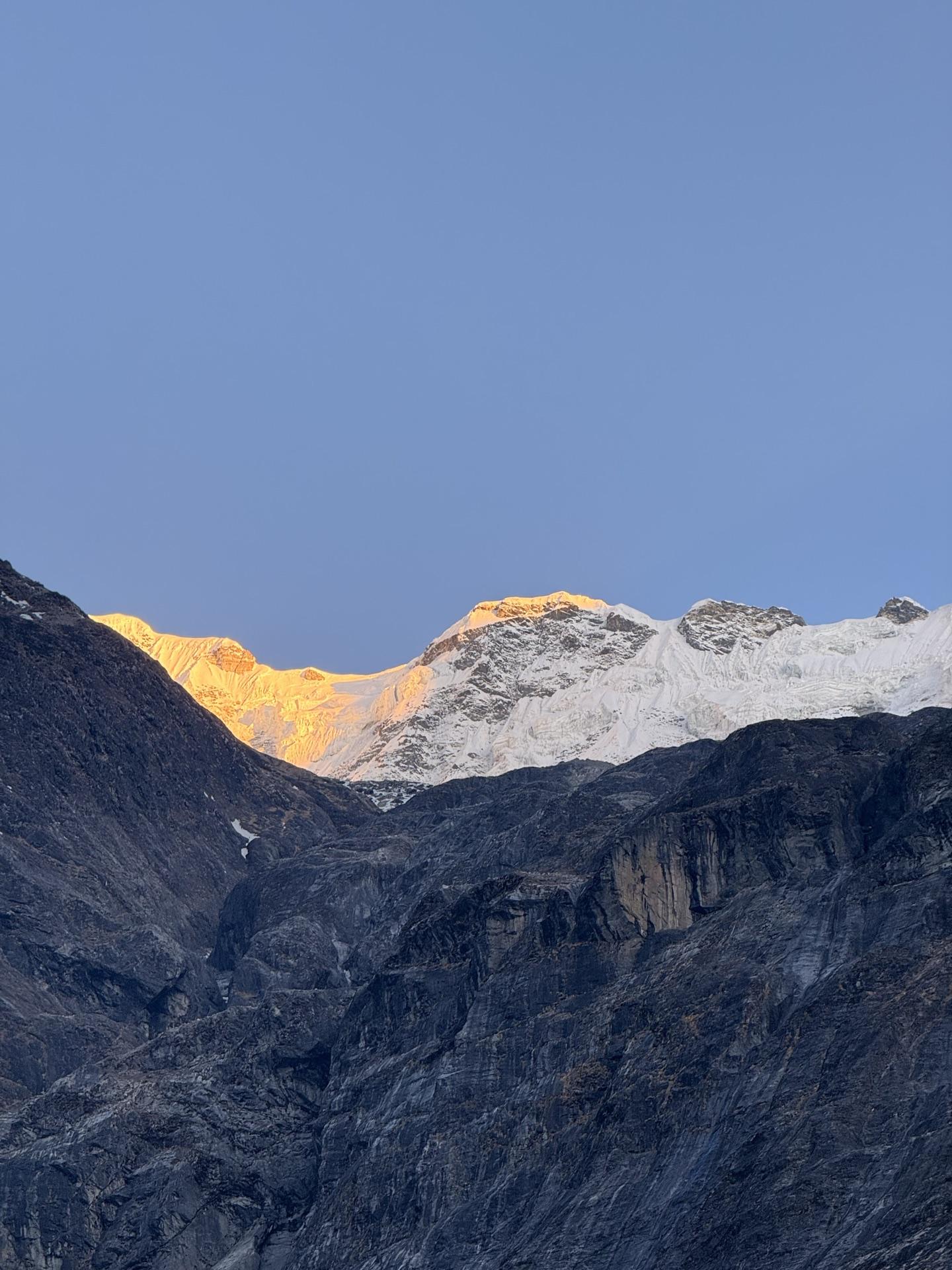 First light catching a snow ridge while the valley sits in blue shadow