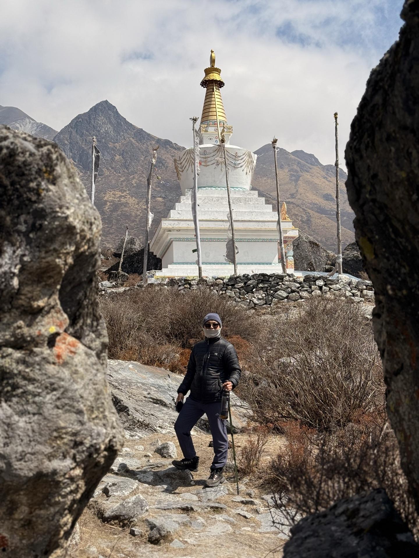 A friend passing a white chorten with a golden spire