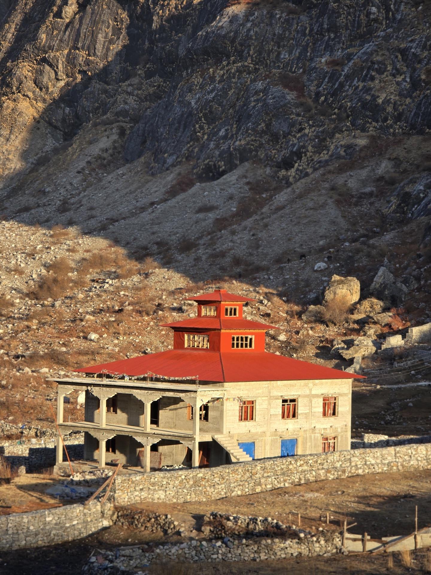 A red-roofed building standing alone in the dry upper valley at first light