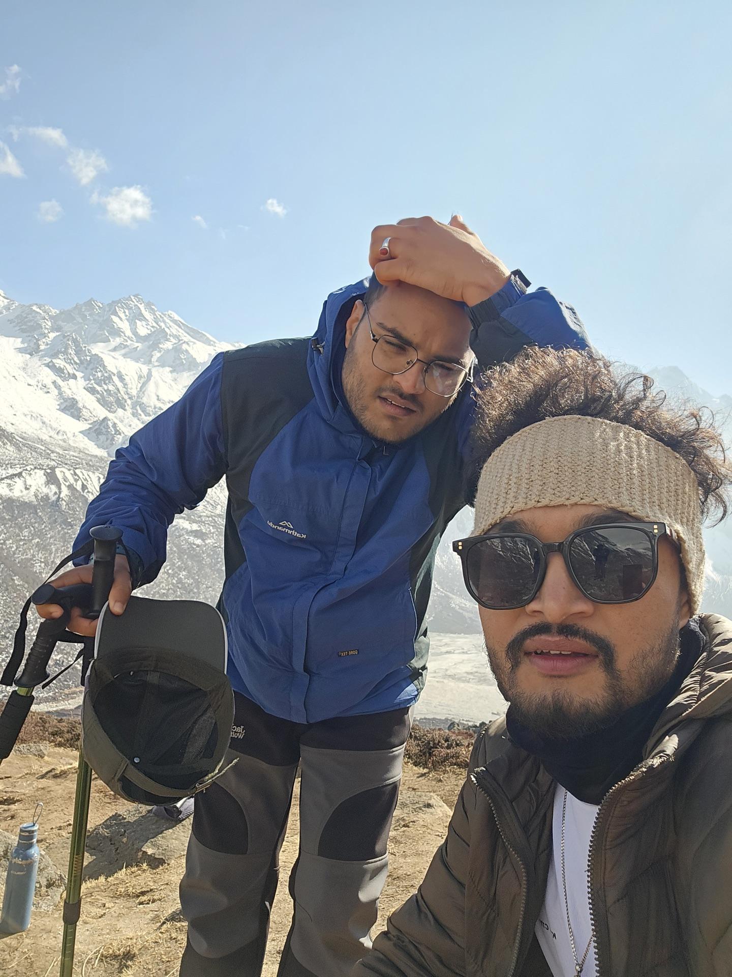 Two friends taking a selfie on the climb, valley far below