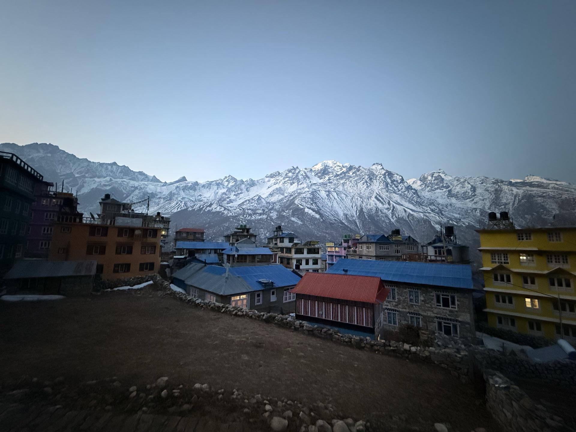 The lodges of Kyanjin Gompa in pre-dawn light with snow peaks behind