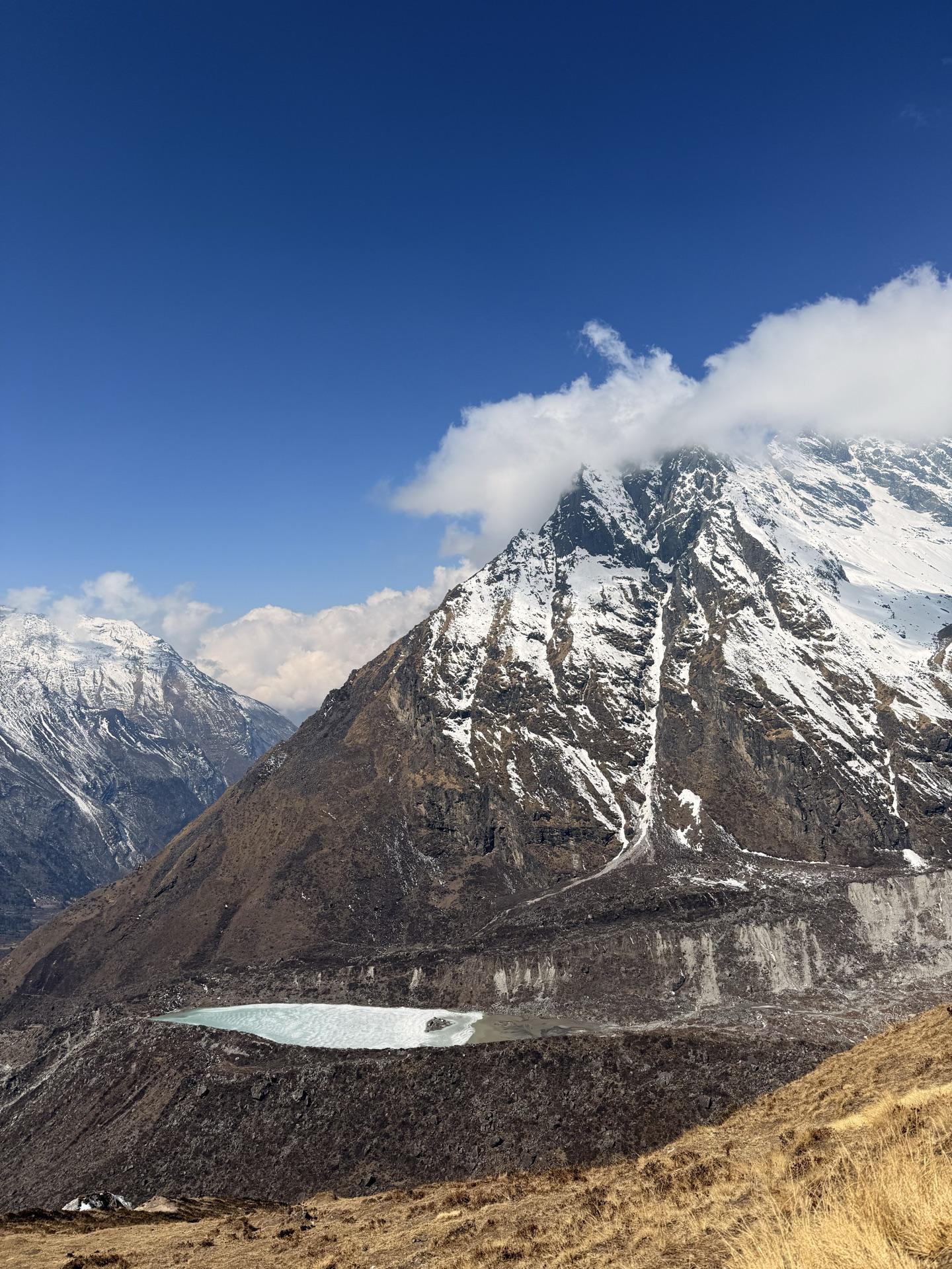 The frozen glacier lake seen tiny and far below from the ridge