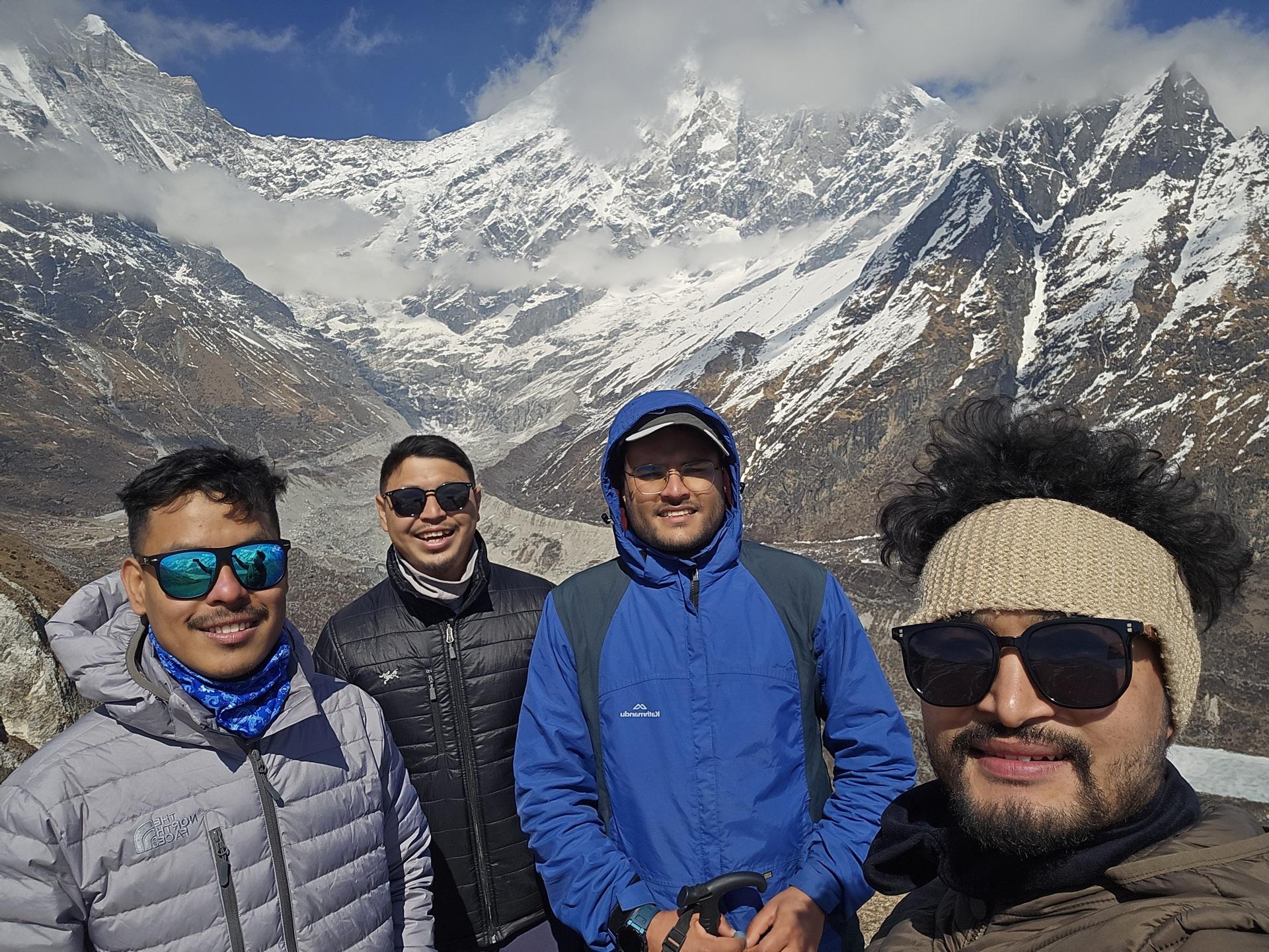 All four friends in a selfie on the high ridge with snow ranges behind