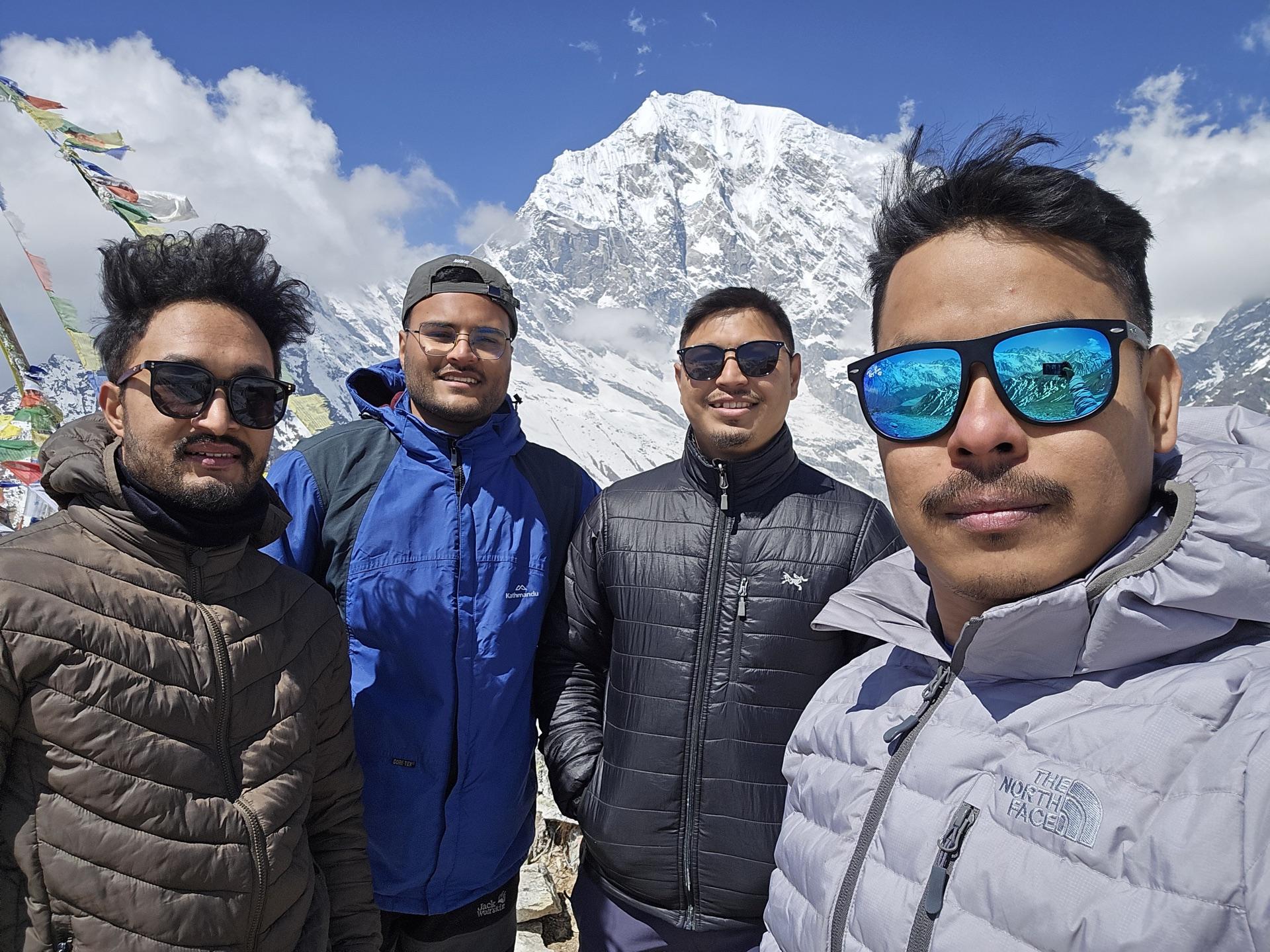 All four friends at the summit, snow massif behind