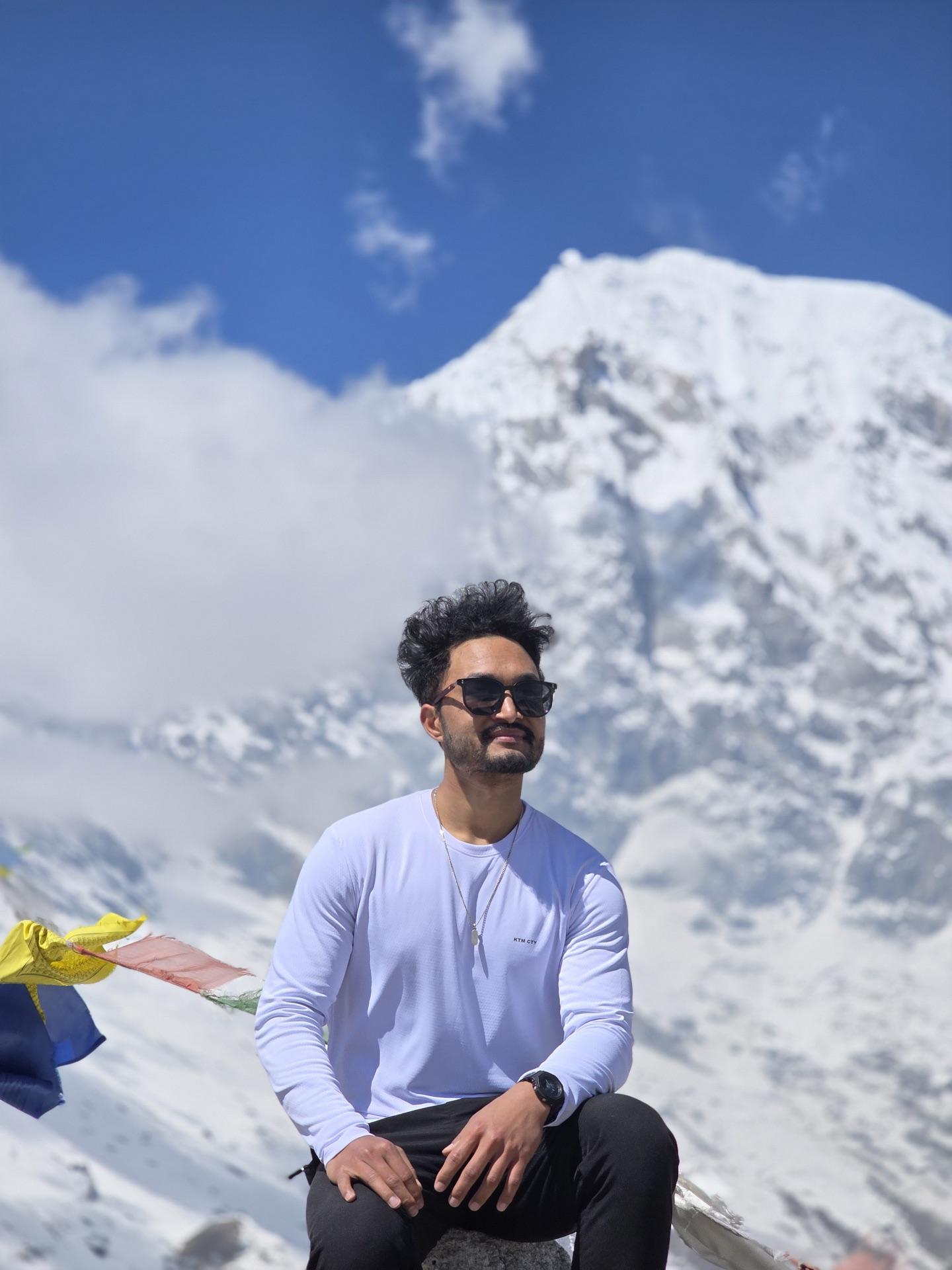 A friend in a white shirt with arms spread wide at the summit