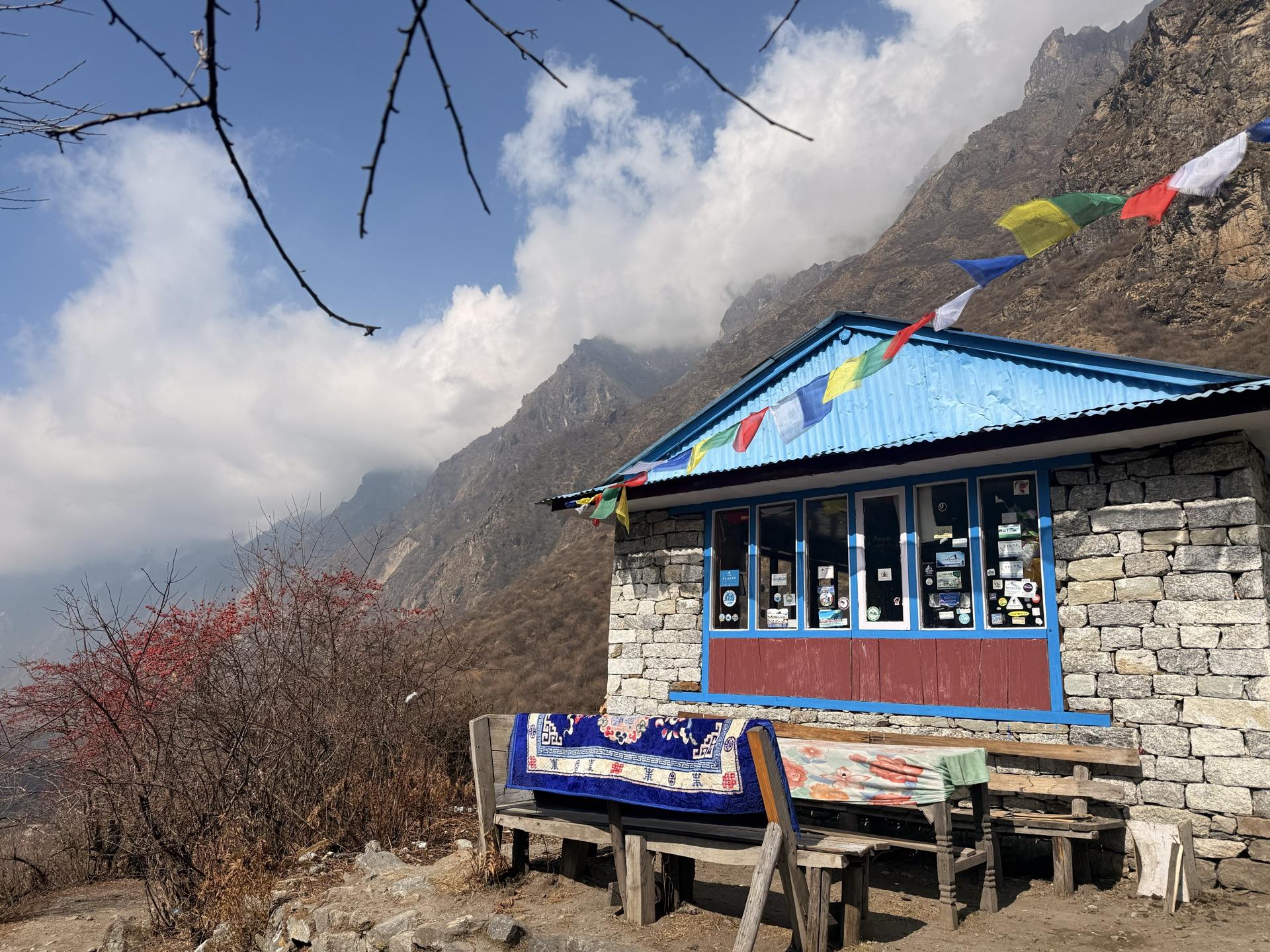 A blue-trimmed teahouse with prayer flags at the edge of the high valley