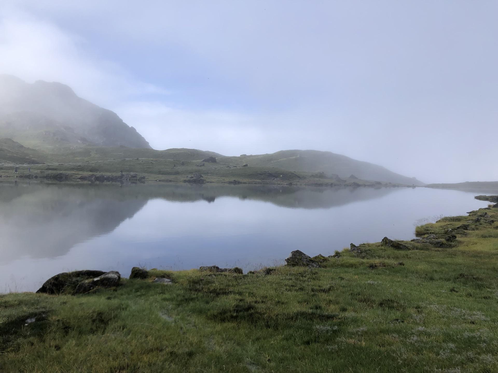 A still lake mirroring the green rocky hills of the basin