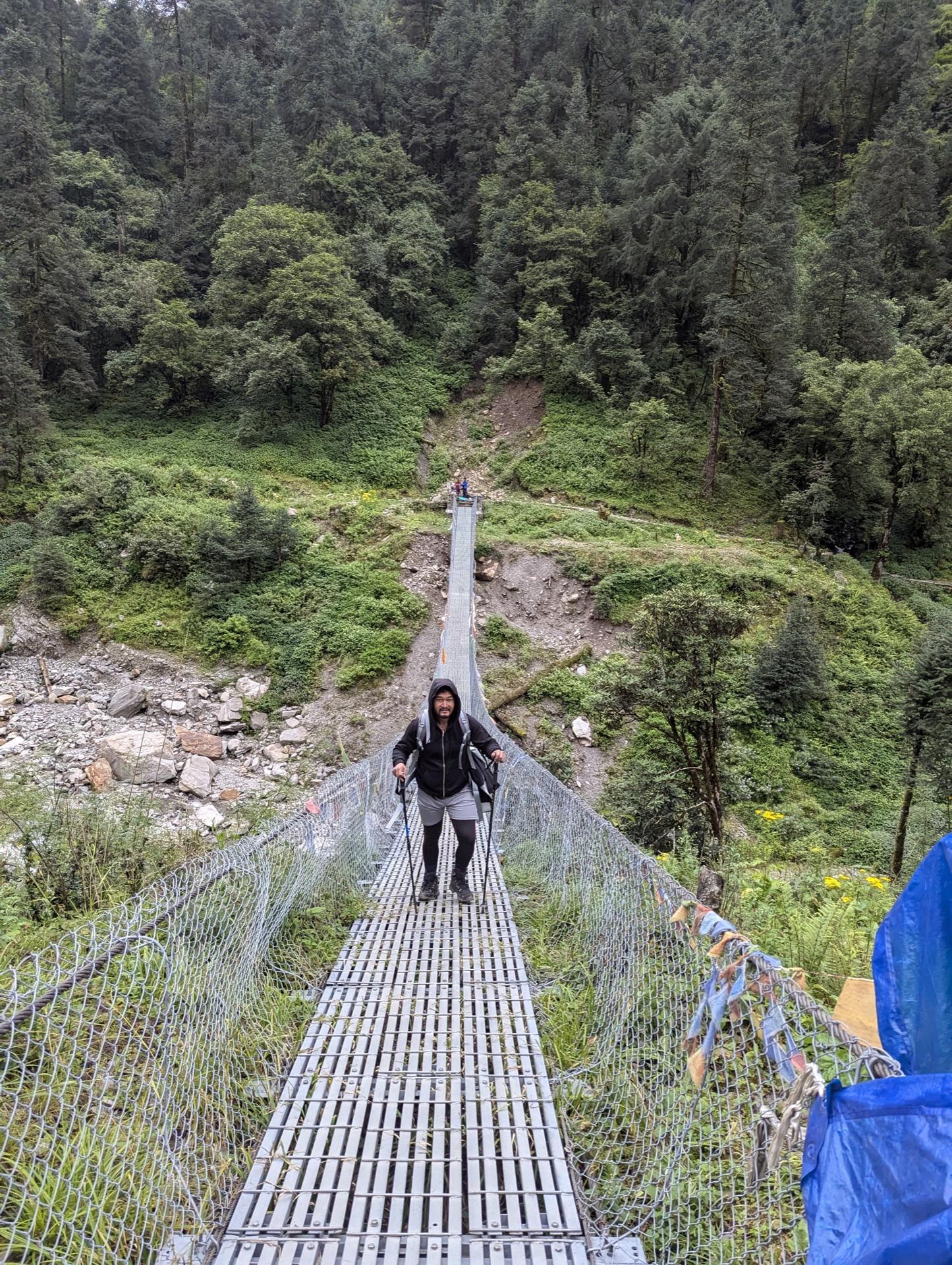 A trekker crossing the suspension bridge on the way down